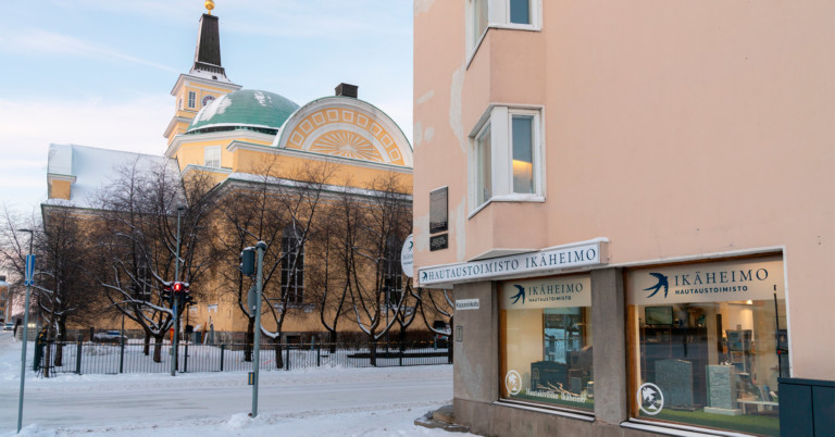 Hautaustoimisto Ikäheimon nettisivuilla julkaistun artikkelin kuvituskuva. Kuvassa Hautaustoimisto Ikäheimon julkisivu talvisessa Oulussa, taustalla näkyy Oulun Tuomiokirkko.